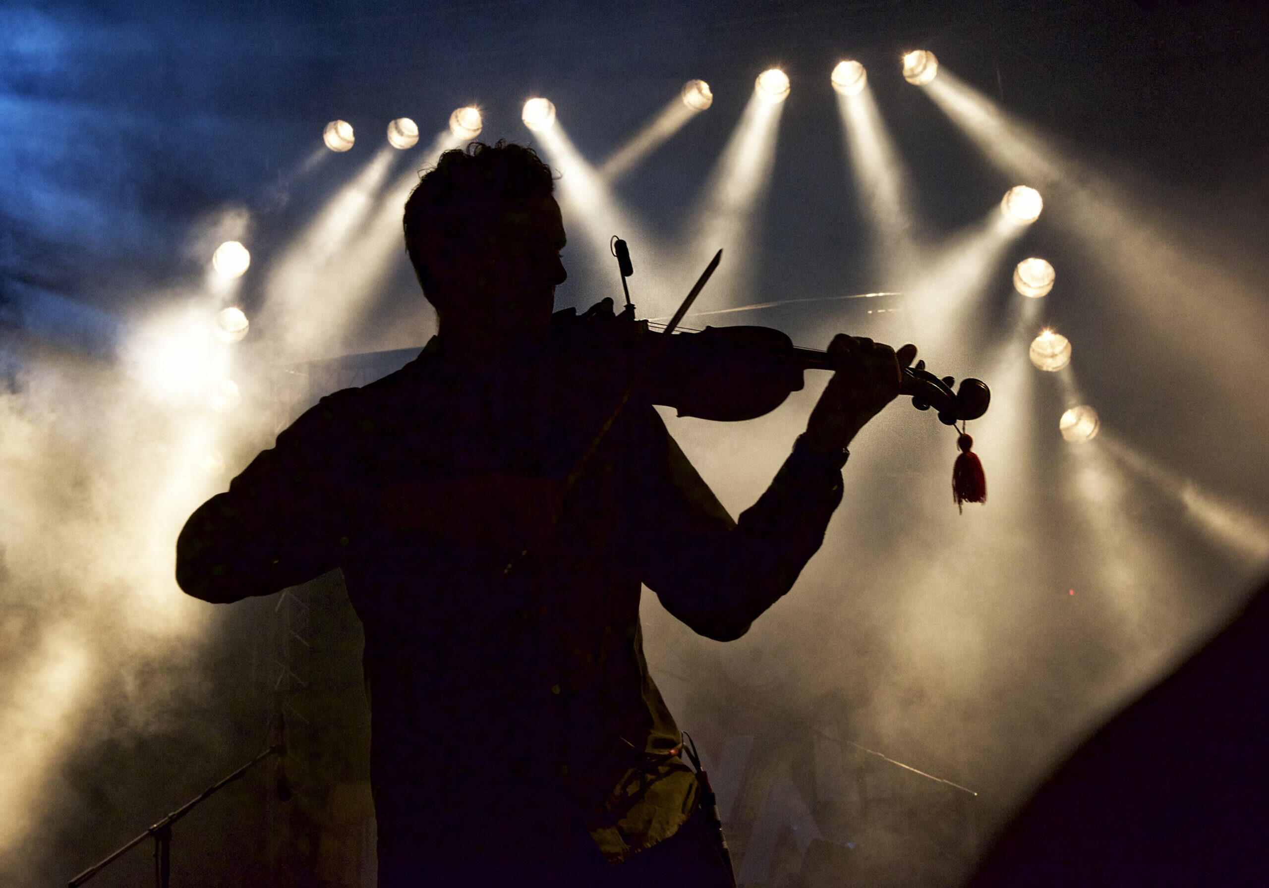 Silhouette of a man on stage playing the violin