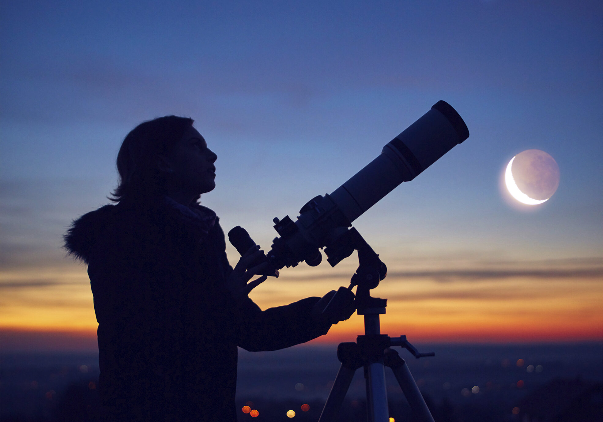Child girl observing stars, planets, Moon and night sky with astronomical telescope.